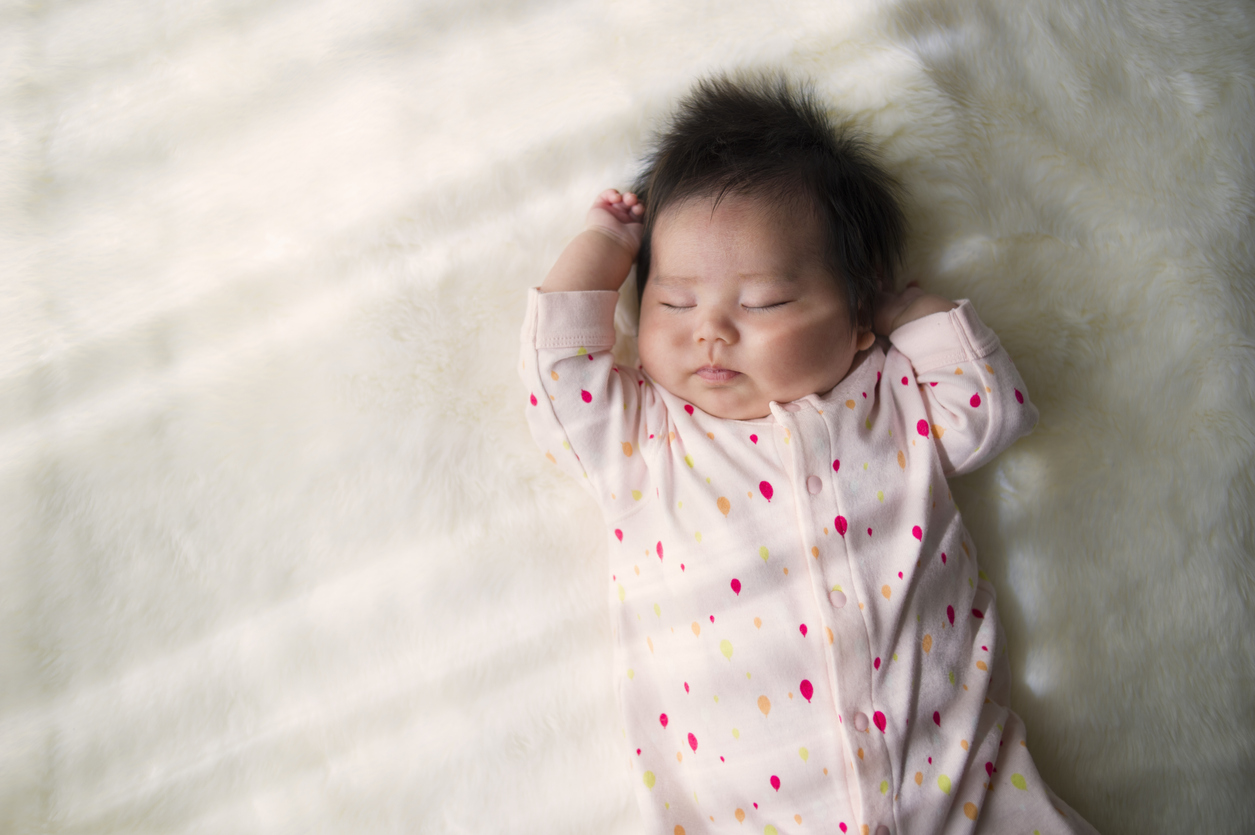 Baby sleeping in white pyjamas with black stars