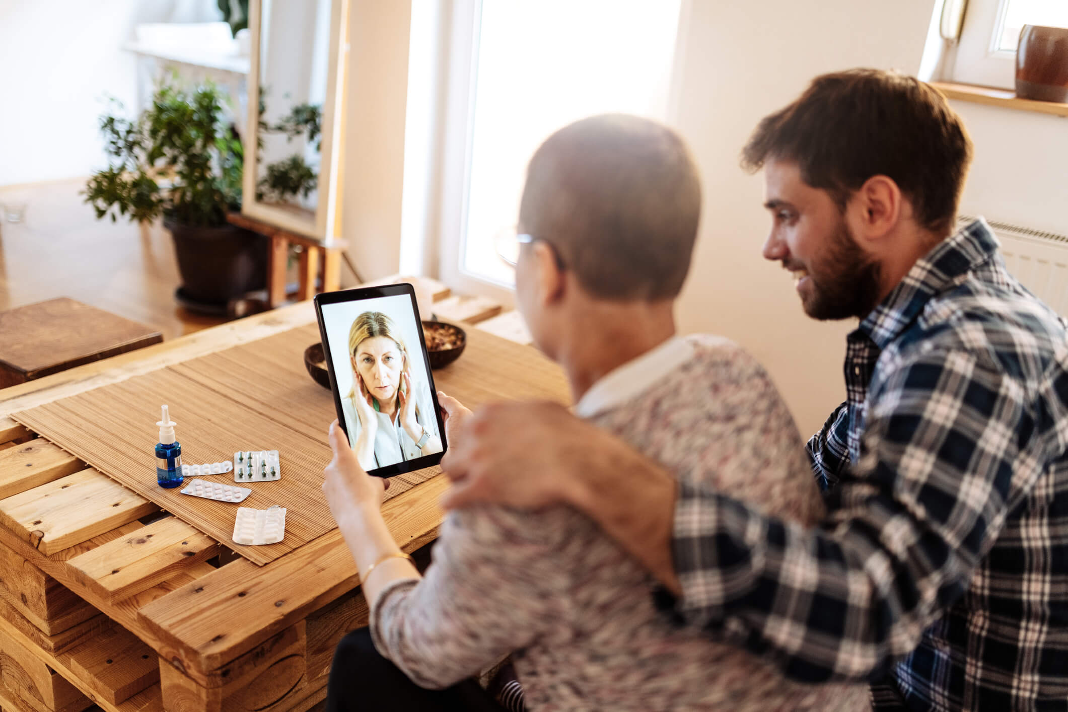 cancer-patient-and-male-friend-talking-to-woman-on-tablet